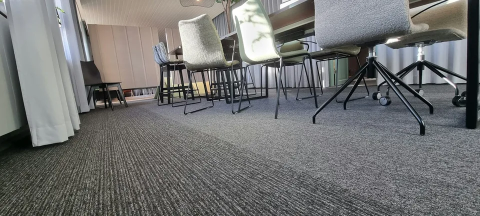 Textured fitted carpet beneath upholstered chairs in a commercial space