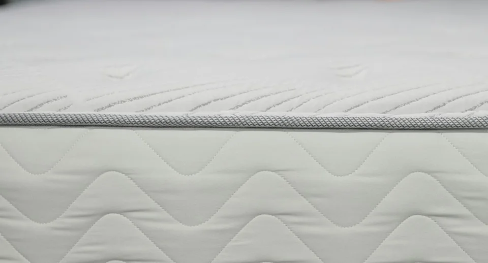 Uncovered white mattress with a quilted sleeping surface and fabric sides